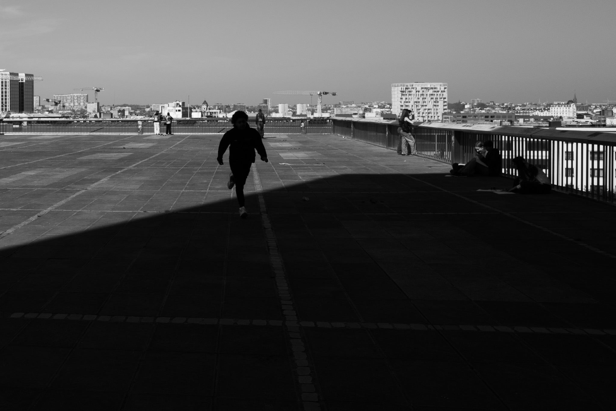 A kid running across a rooftop terrace overlooking the city